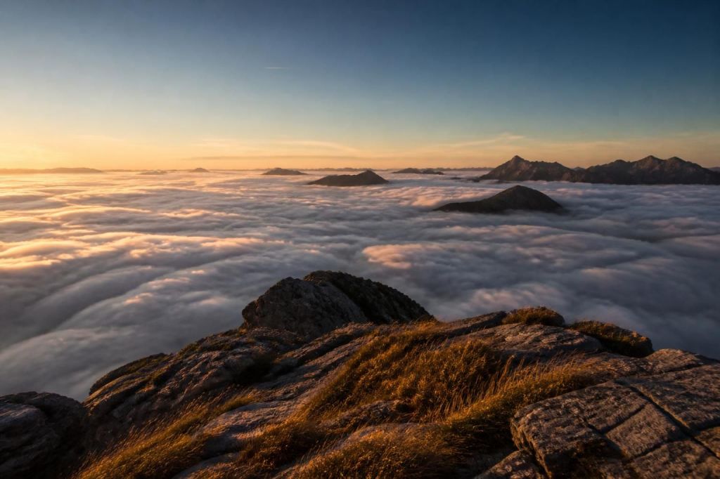 A rocky mountain summit at first light above a sea of clouds